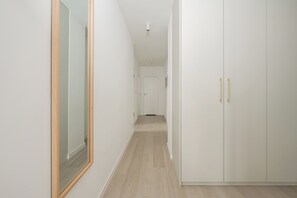 A hallway with a mirror, a wardrobe with gold handles, and a door at the end. - Lumina 4-room Apart, Parking, Balcony (Warszawa)