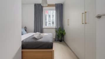 Una camera da letto con un letto, una finestra con tende, una pianta in vaso e un armadio.