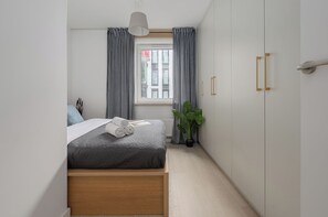 A bedroom with a bed, a window with curtains, a potted plant, and a wardrobe. - Lumina 4-room Apart, Parking, Balcony (Warszawa)