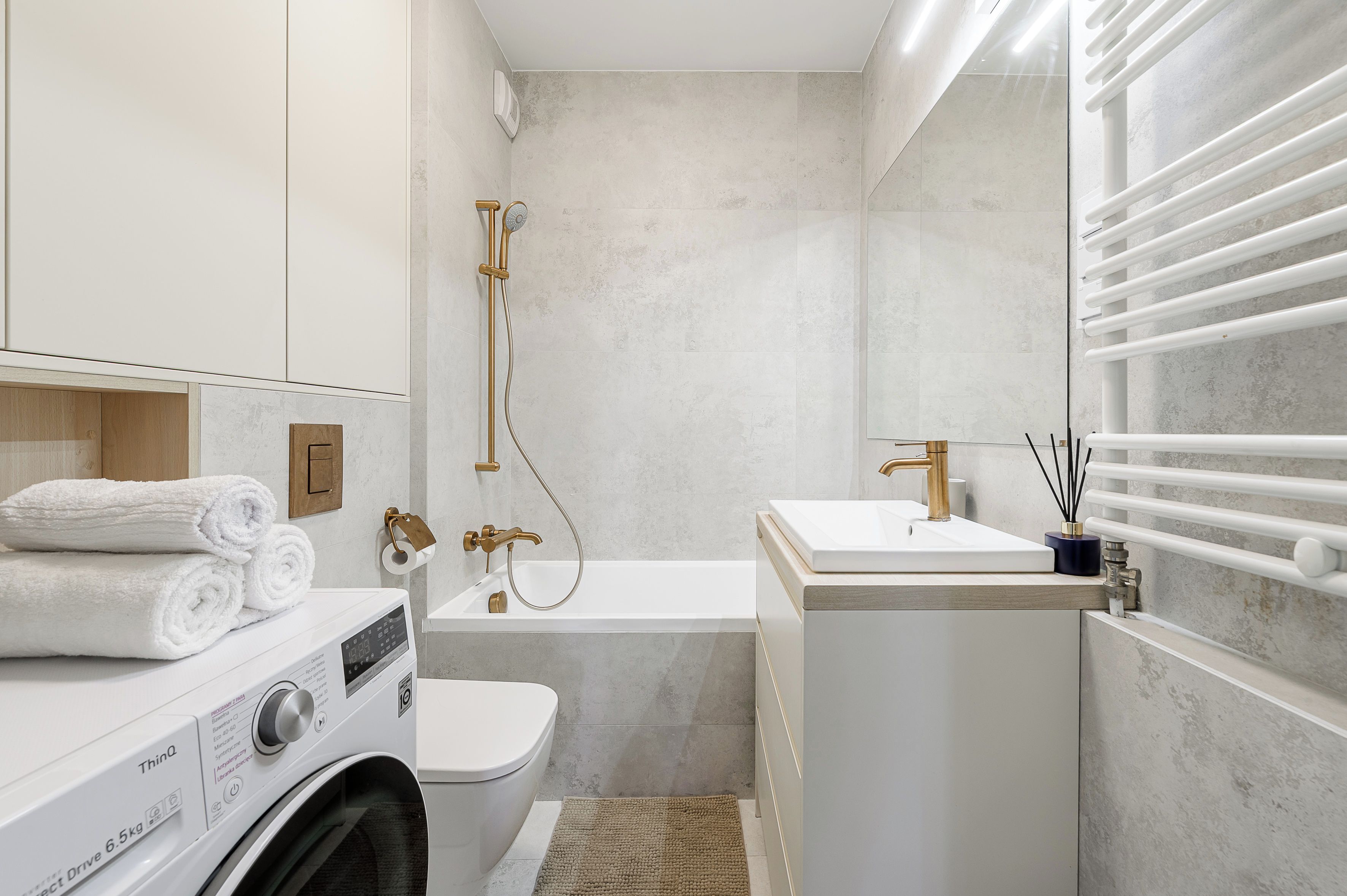 A compact bathroom with a washing machine, toilet, bathtub, and a sink.