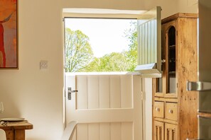 Una habitación con una puerta blanca, un armario de madera y una ventana con vista a los árboles.