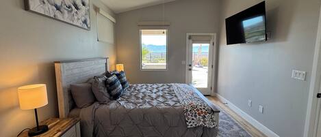 A bedroom with a bed, a nightstand, a TV, and a ceiling fan.