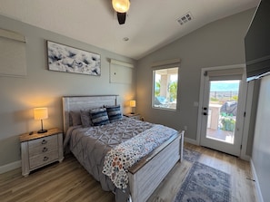 A bedroom with a bed, bedside tables, a nightstand, a window with a view, and a door leading to a balcony. - Mesquite 3BR Home | Private Pool + Slide | Free Activities | Views (Mesquite)
