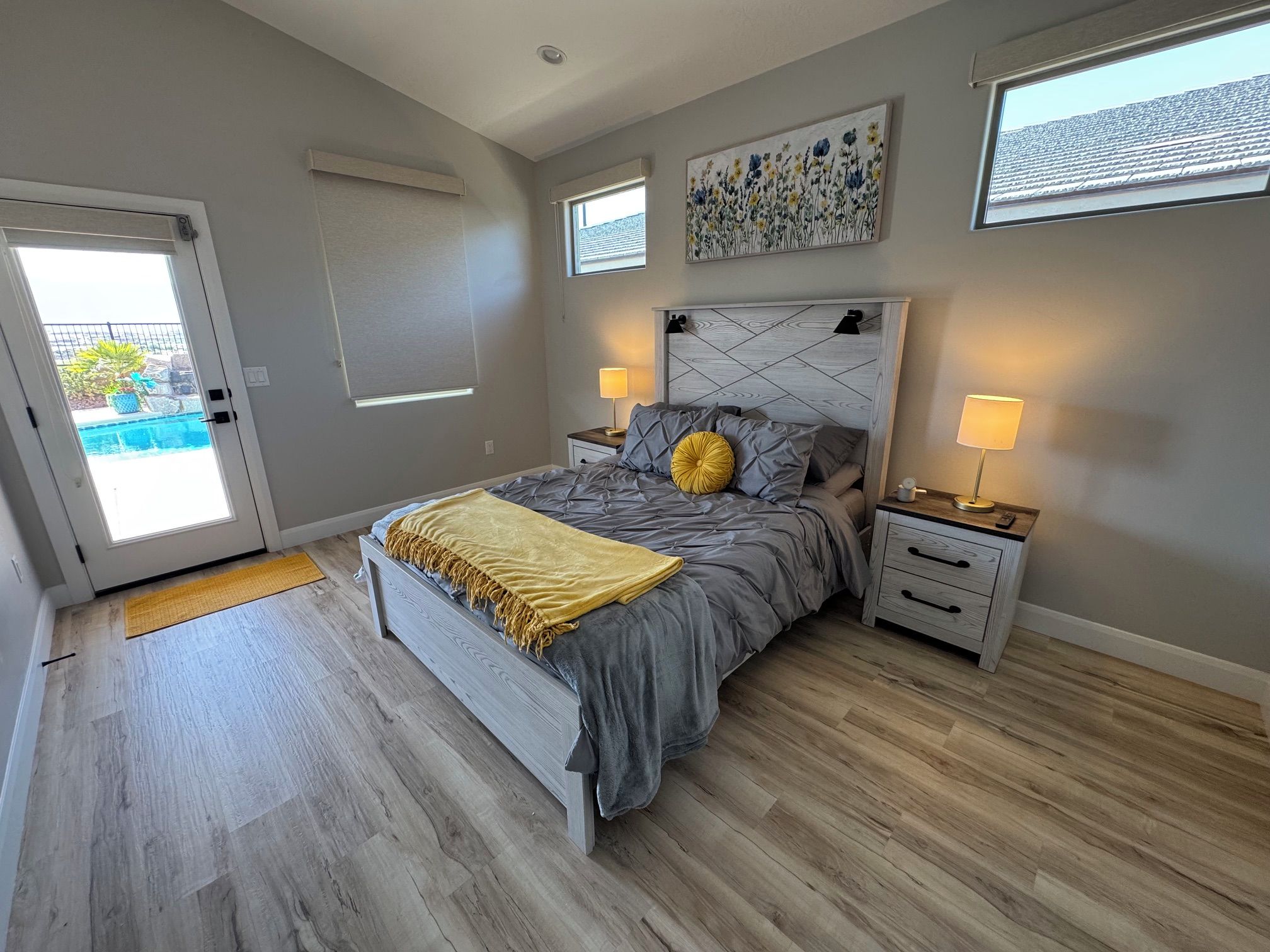 Un dormitorio con cama, mesitas de noche, una ventana y una puerta que da a un balcón.