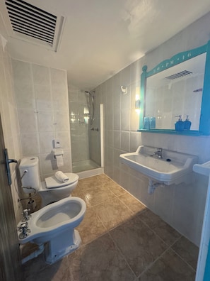 Un baño con inodoro, bidé, ducha y lavamanos.
