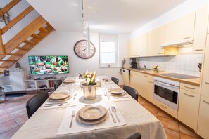 Una cucina moderna con zona pranzo, una sveglia e una televisione che mostra scene di fauna selvatica.