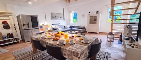 A modern kitchen with a dining area, a refrigerator, and a dining table set for breakfast.