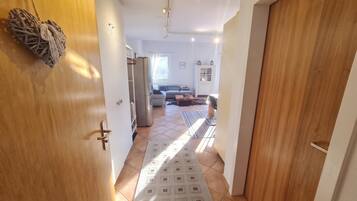 A hallway leading to a living area with a sofa, a rug, and a refrigerator.