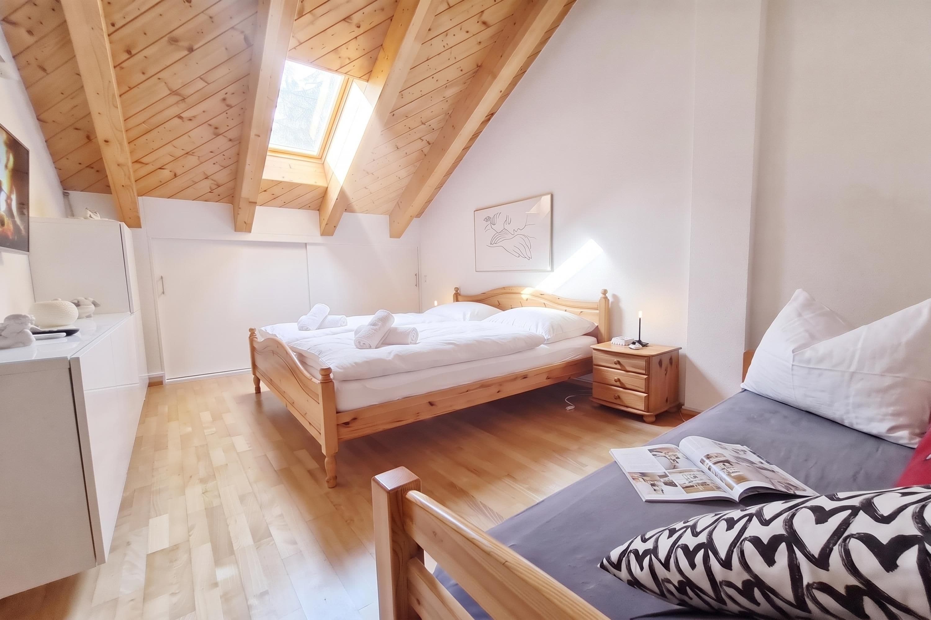 Un dormitorio con una cama de madera, mesitas de noche, un velador, una ventana y un cuadro colgado en la pared.