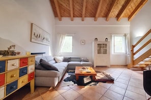 Ein gemütliches Wohnzimmer mit einer Couch, einem Couchtisch, einem farbenfrohen Schrank und einer Treppe.