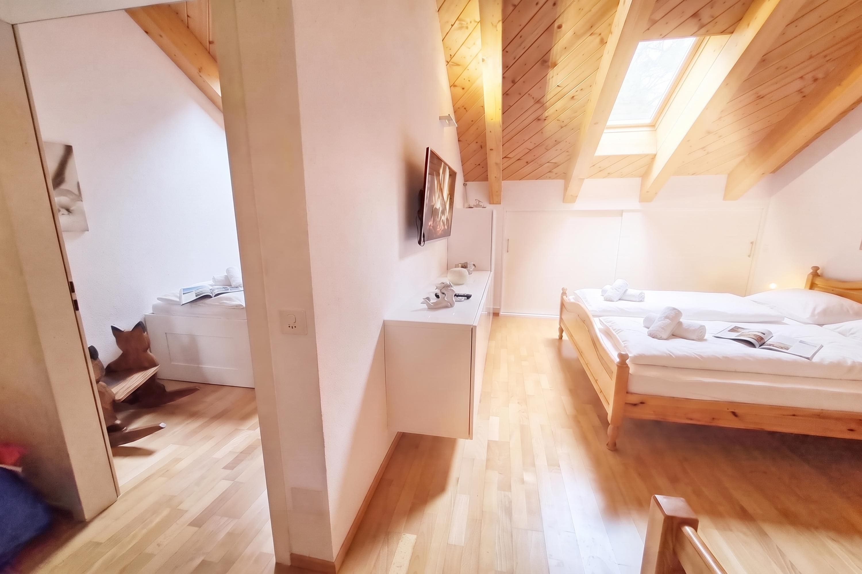 Une pièce avec un plafond en bois, un lit avec une literie blanche et un petit bureau avec une chaise.