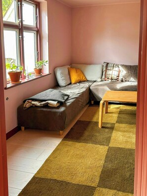 Een gezellige kamer met een bed, een klein tafeltje en een raam met plantenpotten.