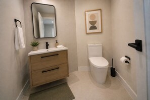 A modern bathroom with a toilet, sink, and mirror. - Huge  Home Near Times Square (New York)