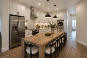 A modern kitchen with stainless steel appliances, a wooden island, and pendant lighting. - Huge  Home Near Times Square (New York)