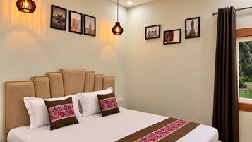 A hotel room with a large bed, multiple pillows, a bedside table with a phone, and framed pictures on the wall.