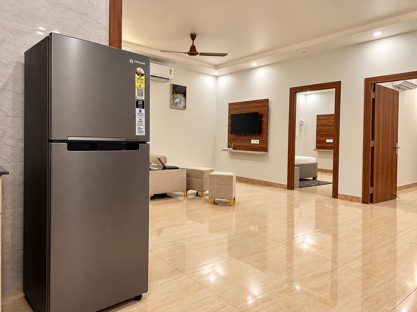 Una cocina moderna con un refrigerador de acero inoxidable, un televisor de pantalla plana montado en la pared y un ventilador de techo.