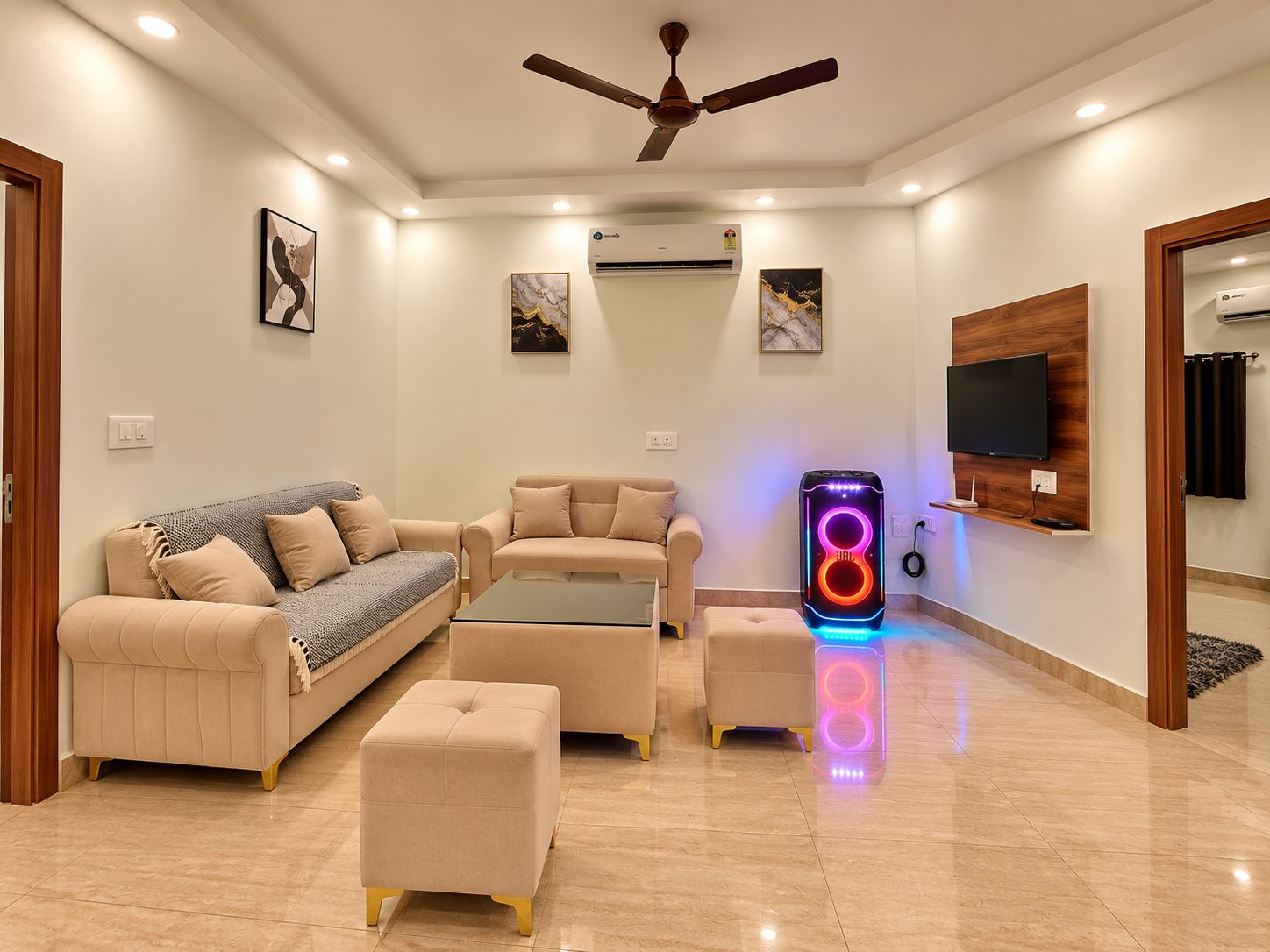 A modern living room with a sofa, ottoman, coffee table, and a gaming console with colorful lights.