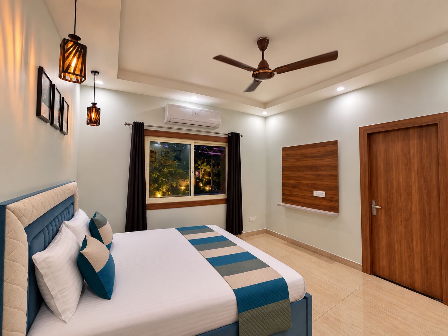 Un dormitorio con una cama, ventilador de techo, ventana con cortinas y puerta de madera.