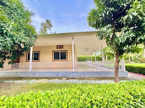 A building with a covered entrance, a white railing, and a paved area in front. - Mulberry Farm (Noida)