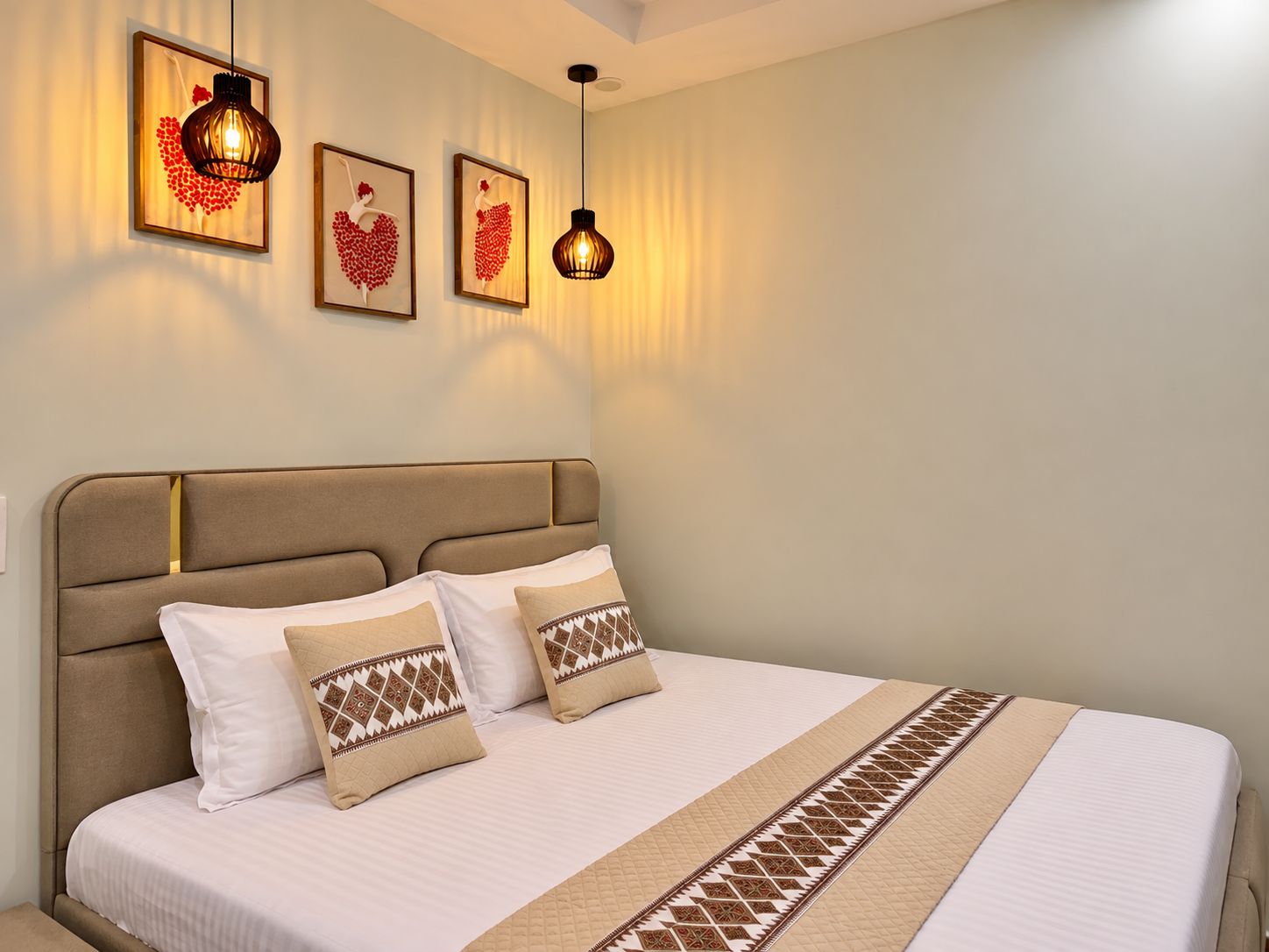 Habitación de hotel con una cama grande, cabecera y dos lámparas fijadas a la pared.