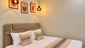 Habitación de hotel con una cama grande, cabecera y dos lámparas fijadas a la pared.
