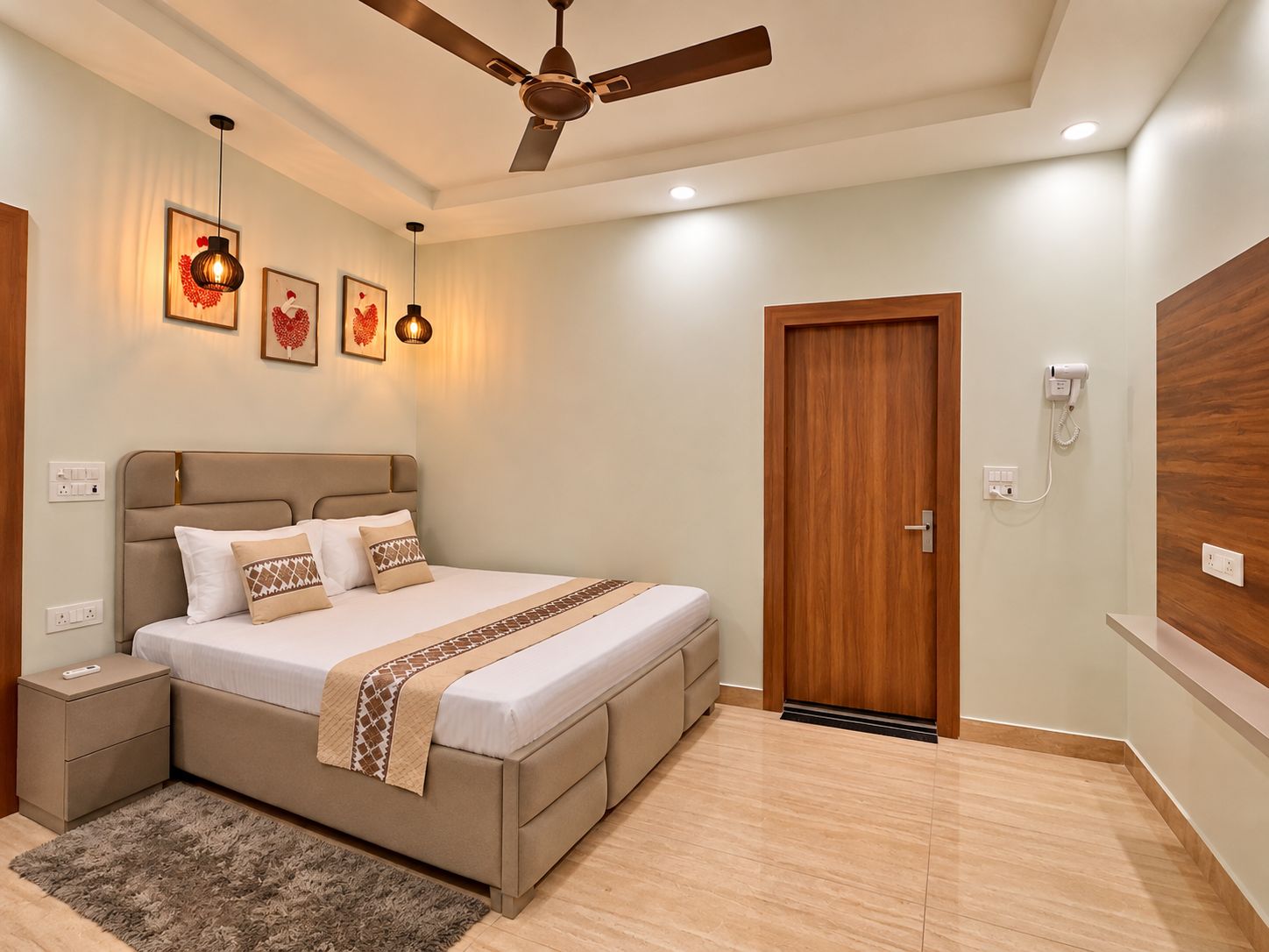 A bedroom with a bed, bedside tables, a ceiling fan, wall-mounted lights, and a door with a phone.