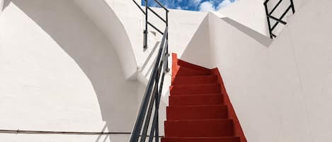 A white building with a red staircase and black railings.
