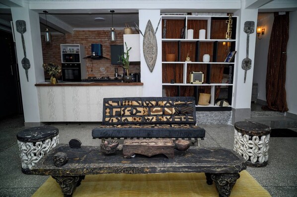 A living room with a sofa, two side tables, a coffee table, and a kitchen in the background.