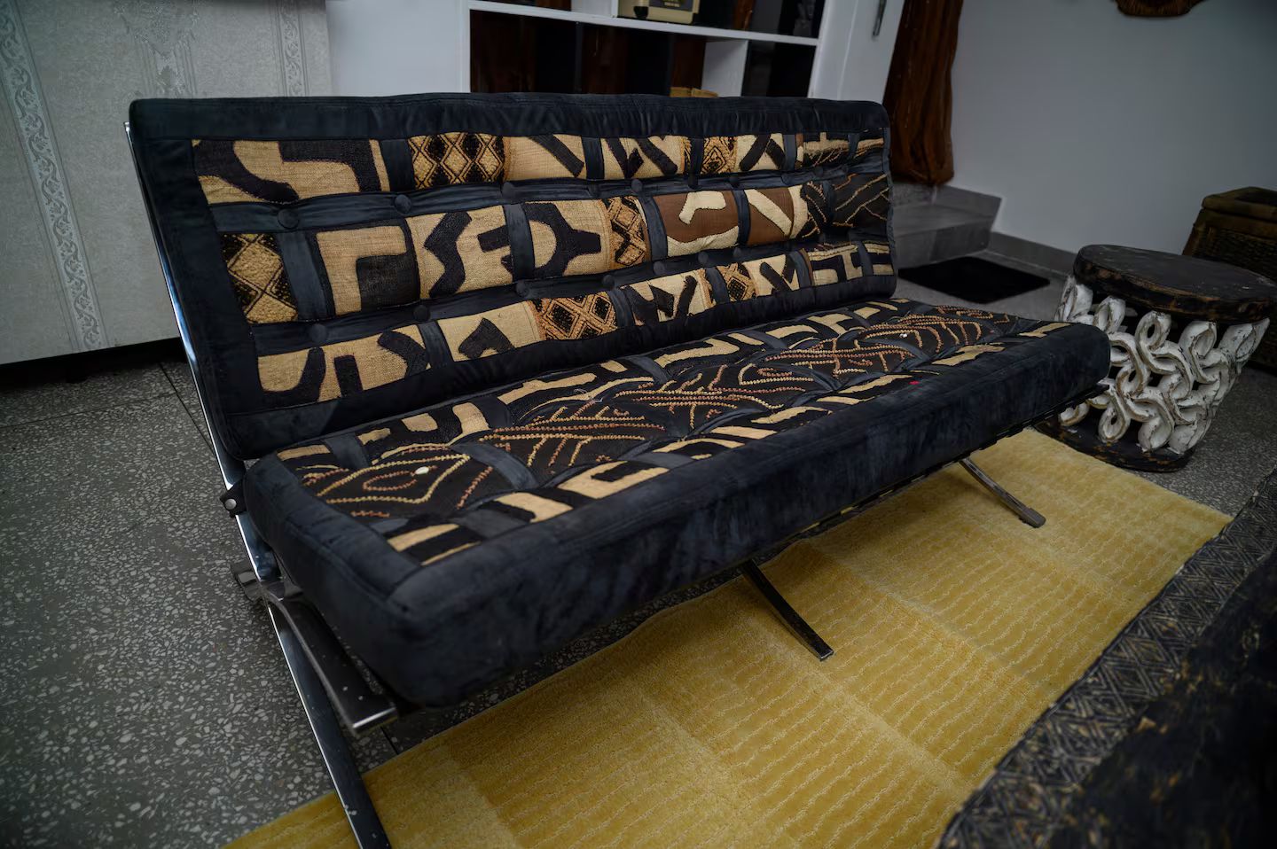 Un sofá con un respaldo estampado y un cojín a juego, sobre una alfombra amarilla.