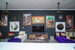 A living room with a flat-screen TV, a sofa, a coffee table, and a fireplace. - Art Gallery Villa at Forest Hill House (Lusaka)