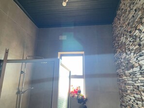 A room with a stone wall, a metal door, and a ceiling fan. - Art Gallery Villa at Forest Hill House (Lusaka)