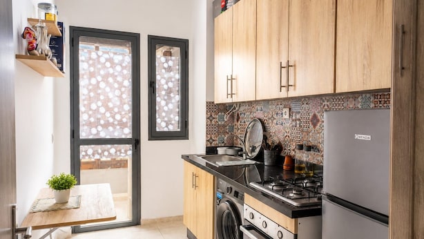 A compact kitchen with a washing machine, a stove, and a refrigerator. - Family Comfort House 77 (Témara)