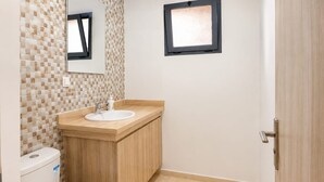 A bathroom with a toilet, sink, and mirror. - Family Comfort House 77 (Témara)