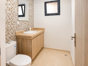 Een badkamer met toilet, wastafel en spiegel.