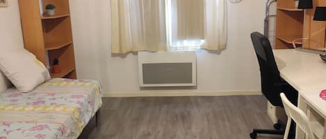 Une pièce comprenant un lit, un bureau, une chaise et un radiateur.