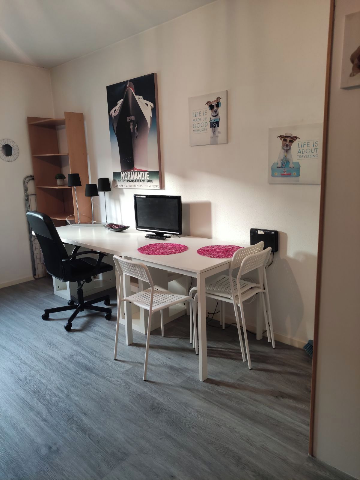A room with a white desk, two black chairs, a computer, and a poster on the wall.
