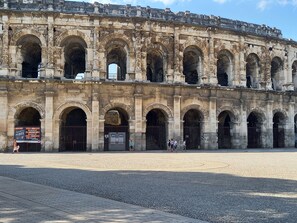 An ancient stone building with multiple arches and a paved courtyard. - LE 63 at Les Arènes (Nîmes)