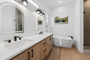 A modern bathroom with a large vanity, a freestanding bathtub, and a wall-mounted mirror. - Trailside MTB Retreat with Sauna (Bella Vista)
