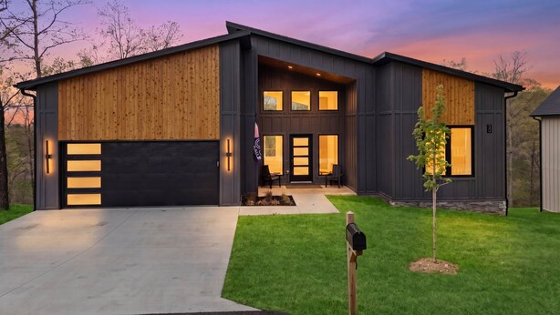 Uma casa moderna de dois andares com garagem, varanda frontal e gramado bem cuidado.