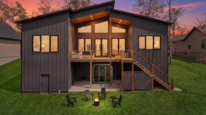 A modern two-story house with a balcony, a fireplace, and outdoor seating. - Trailside MTB Retreat with Sauna (Bella Vista)