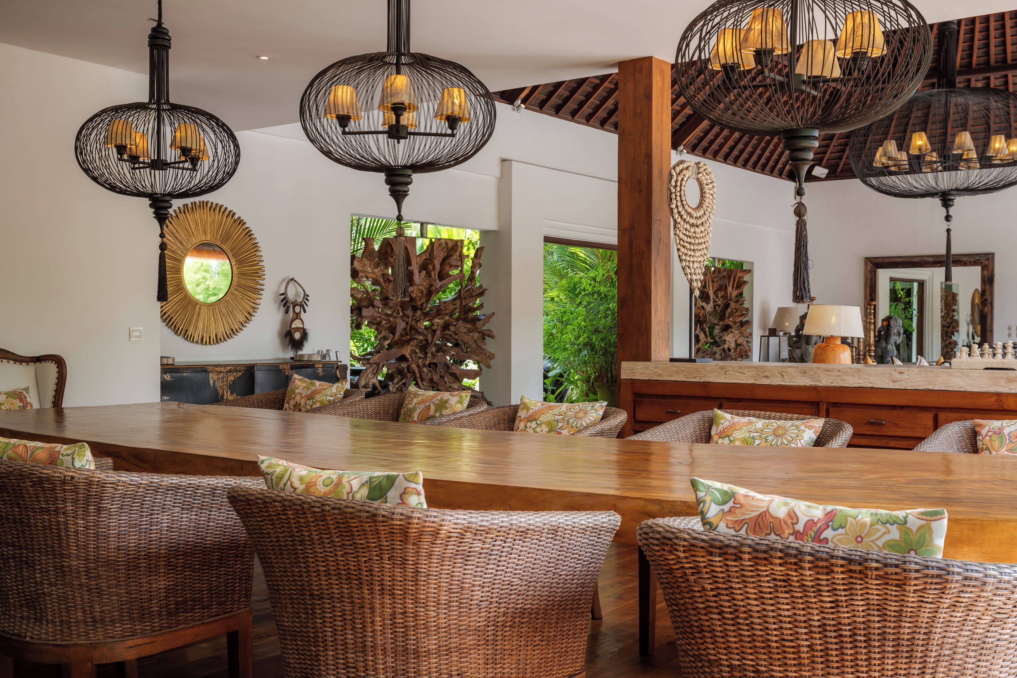 A spacious dining area with wicker furniture and pendant lighting.