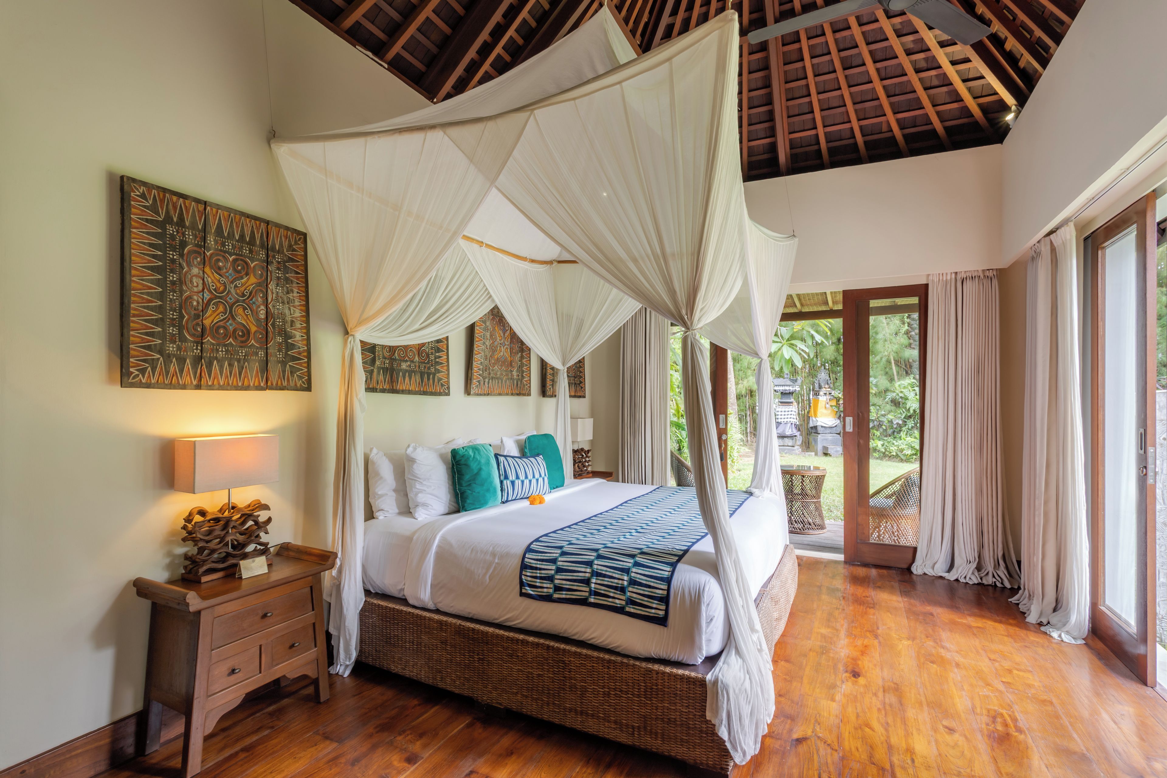 Una habitación con cama con dosel, una mesita de noche con lámpara y vistas al exterior.