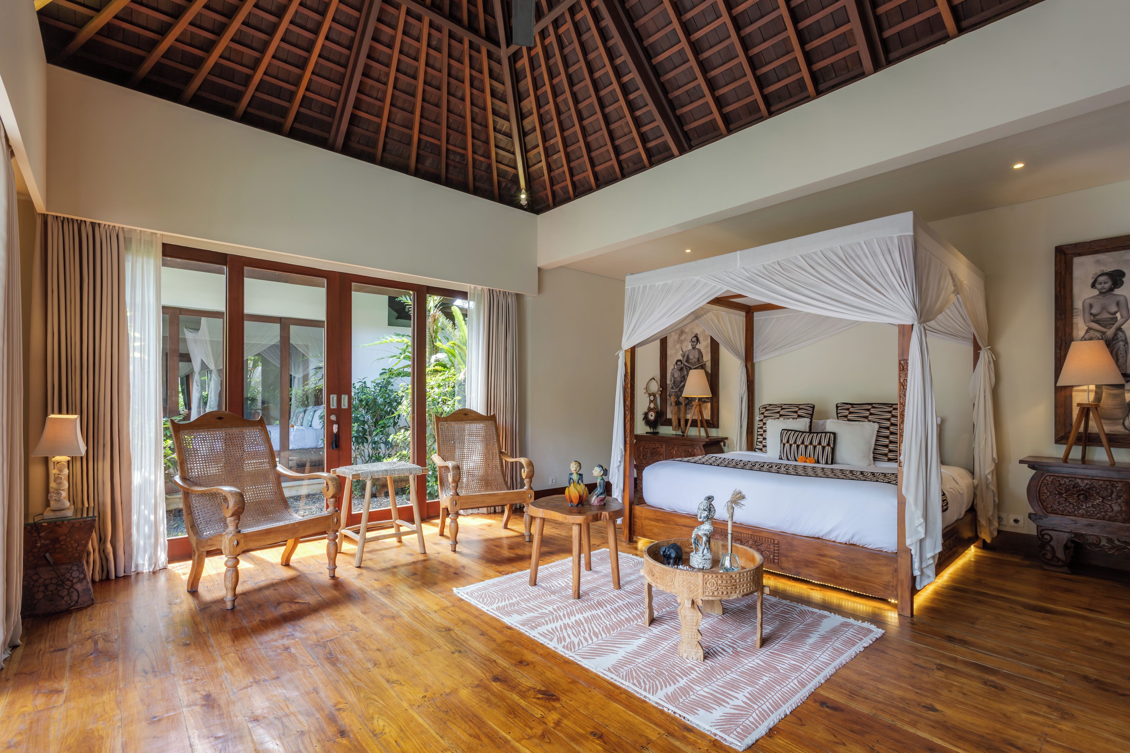 Um quarto espaçoso com uma cama grande, dossel e vista para o verde lá fora.