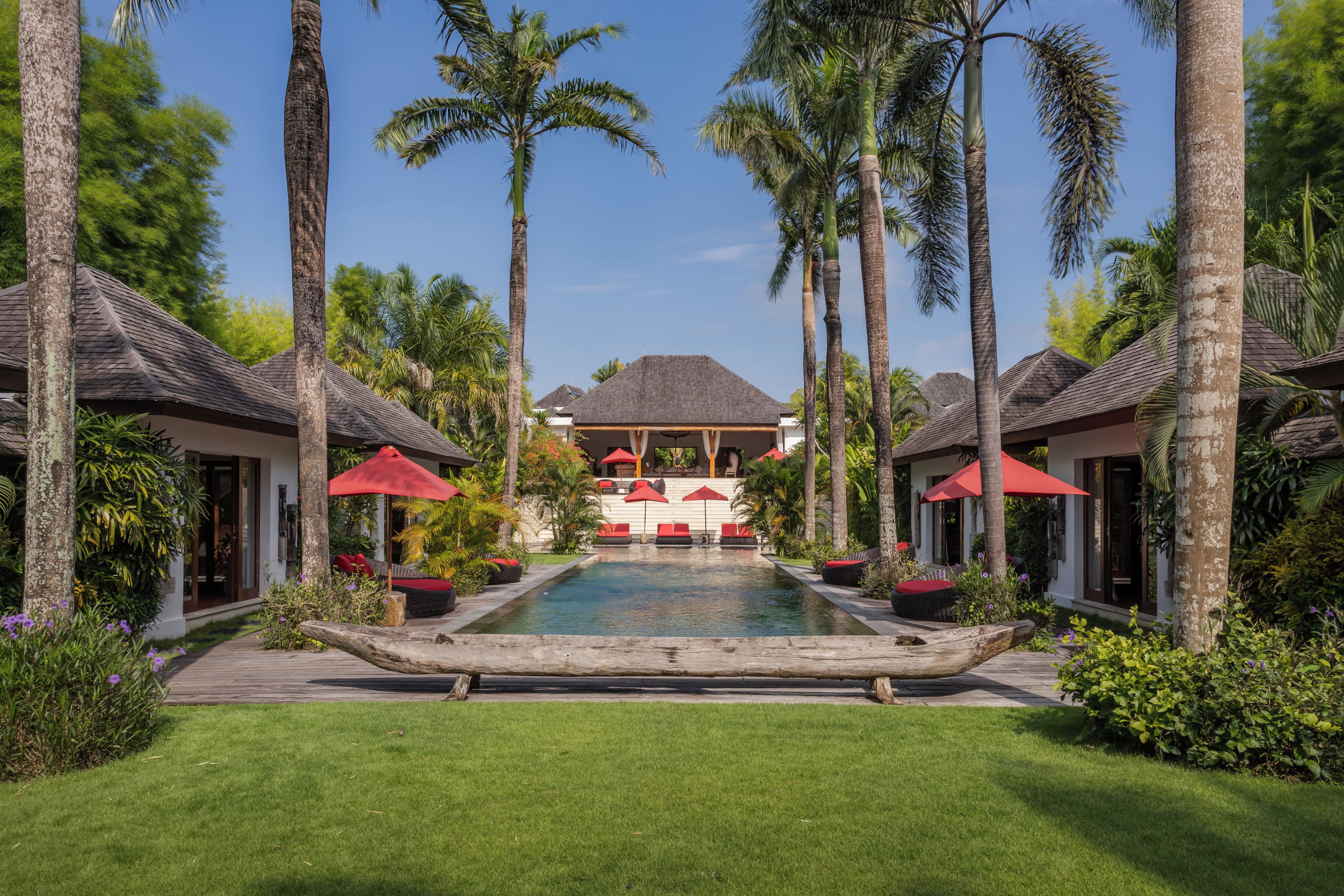 A resort with a central pool, lounge chairs, and palm trees.
