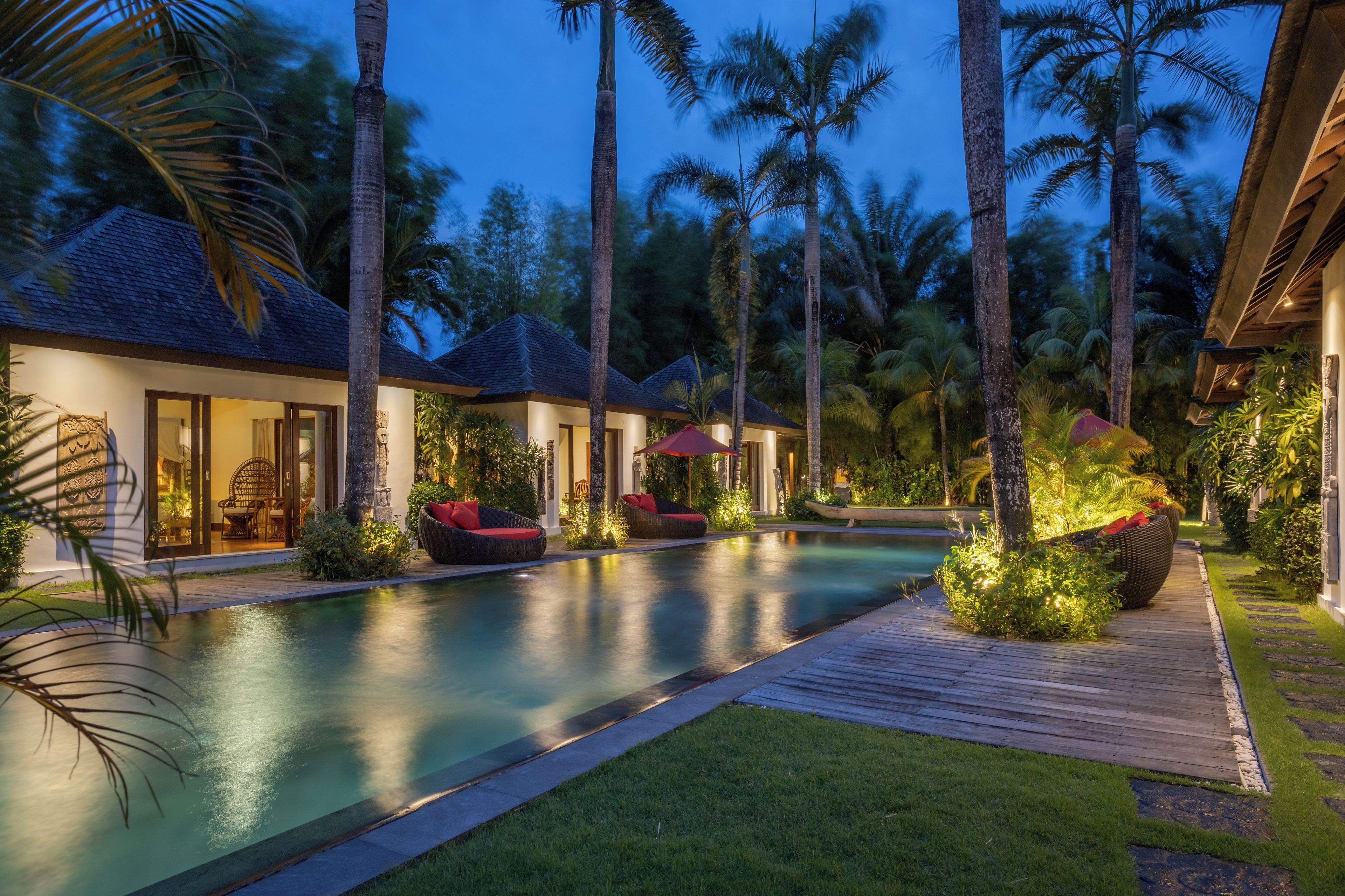 A resort with a swimming pool, palm trees, and a wooden deck.