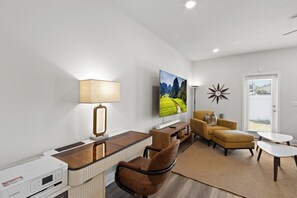 A modern living room with a flat-screen TV, a lamp, a sofa, and a coffee table. - New 2023 Gulf Breeze townhome sleeping 4 across 3 bedrooms, 2.5 baths. King bed, full bunk room, full kitchen, in-unit laundry, dual workspaces & Sonos sound. Minutes to Pensacola Beach, the zoo & Navy bases. Ideal for families or TDY stays. (Gulf Breeze)