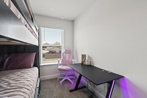 Ein Schlafzimmer mit einem Bett, einem Schreibtisch, einem Stuhl und einem Fenster.