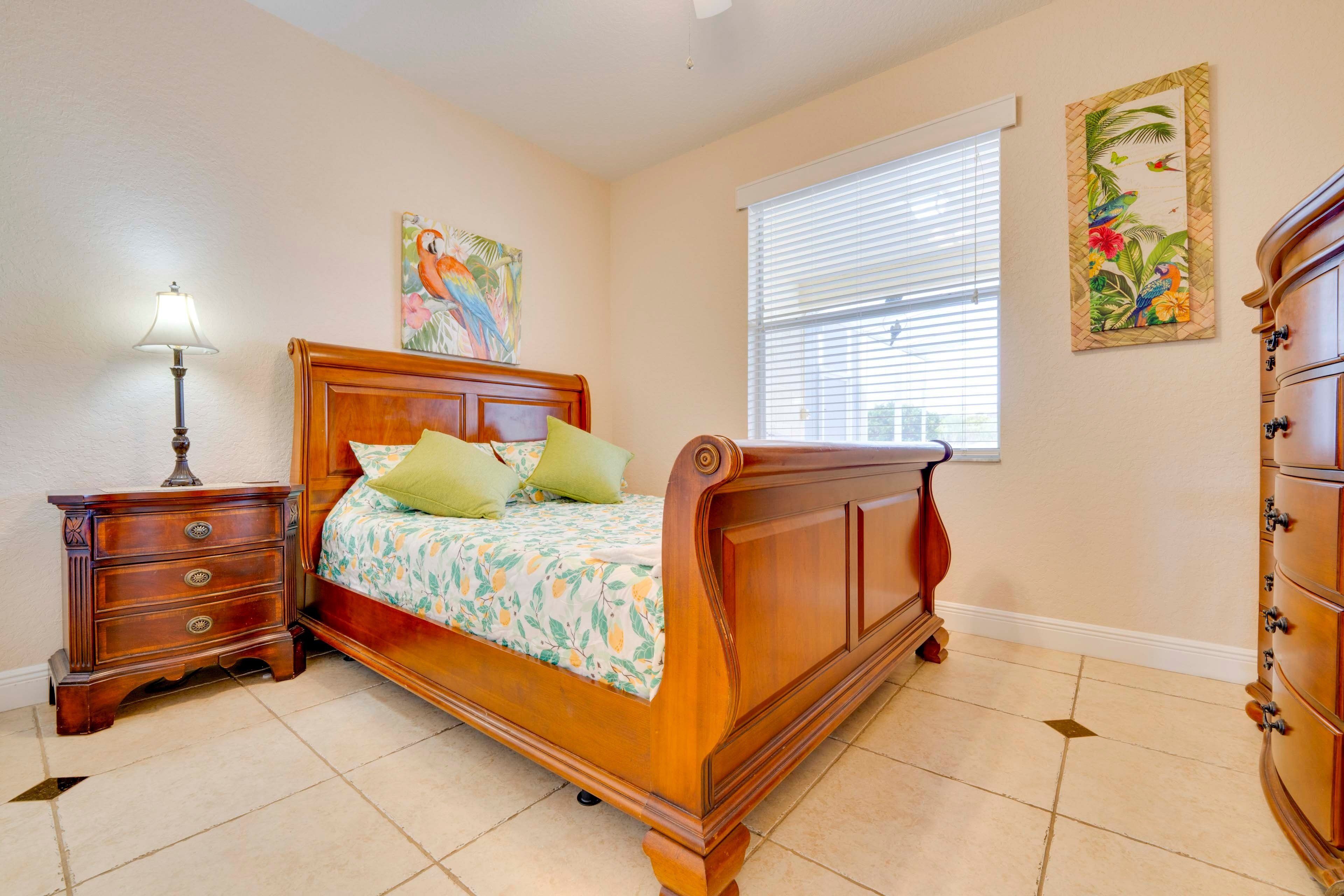 A bedroom with a wooden bed, a nightstand, a dresser, and two wall-mounted paintings.
