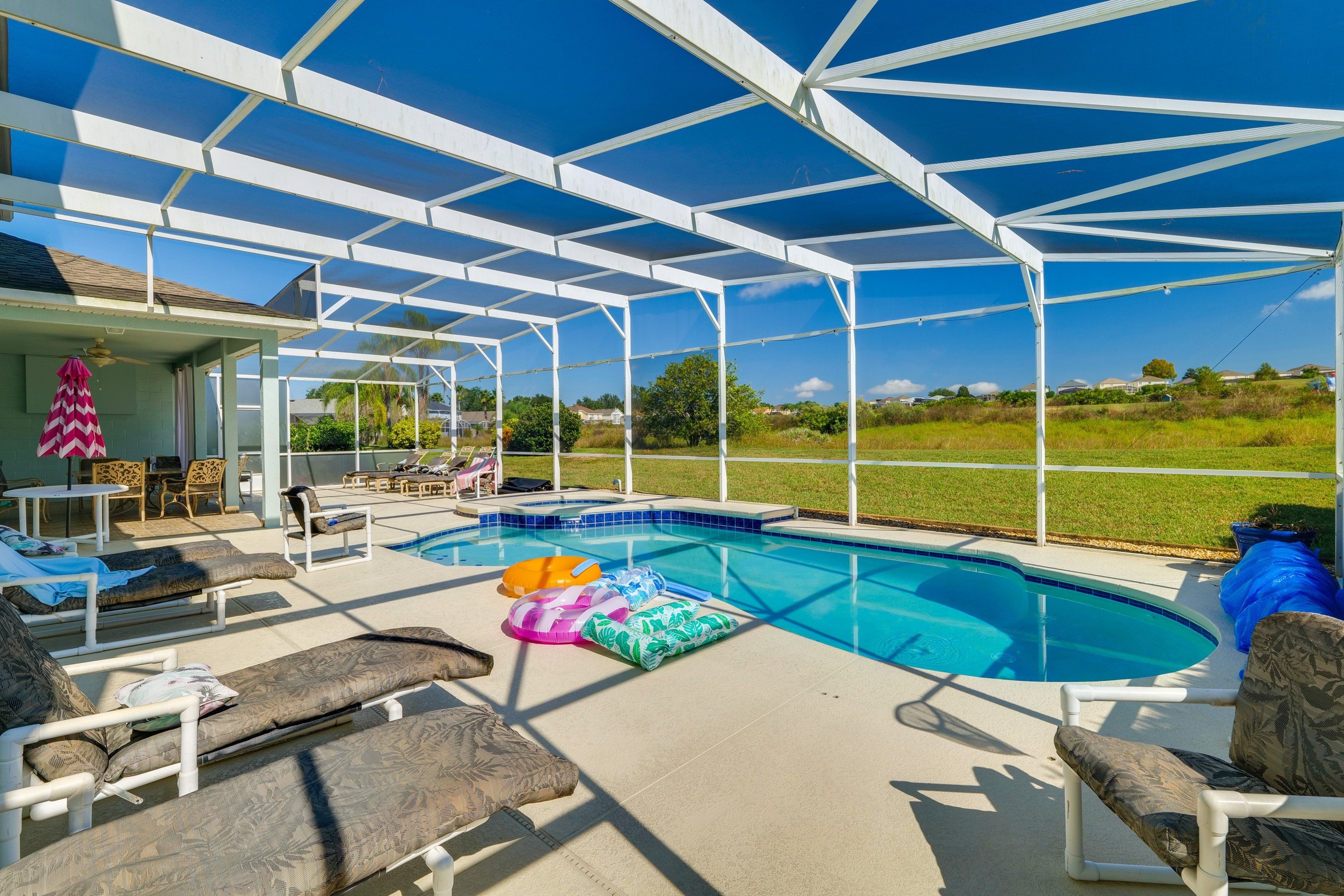 A covered outdoor swimming pool with lounge chairs and a hot tub.