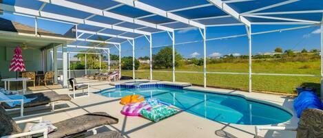 A covered outdoor swimming pool with lounge chairs and a hot tub.